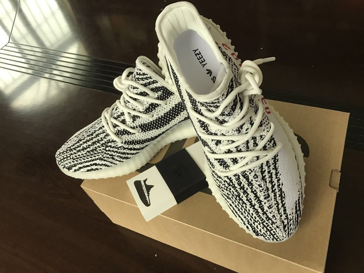 Yeezy 350 V2 Glow-in-the-Dark Sneakers, in Black and White - product image from the listing.