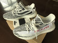 Yeezy 350 V2 Glow-in-the-Dark Sneakers, in Black and White - product image from the listing.